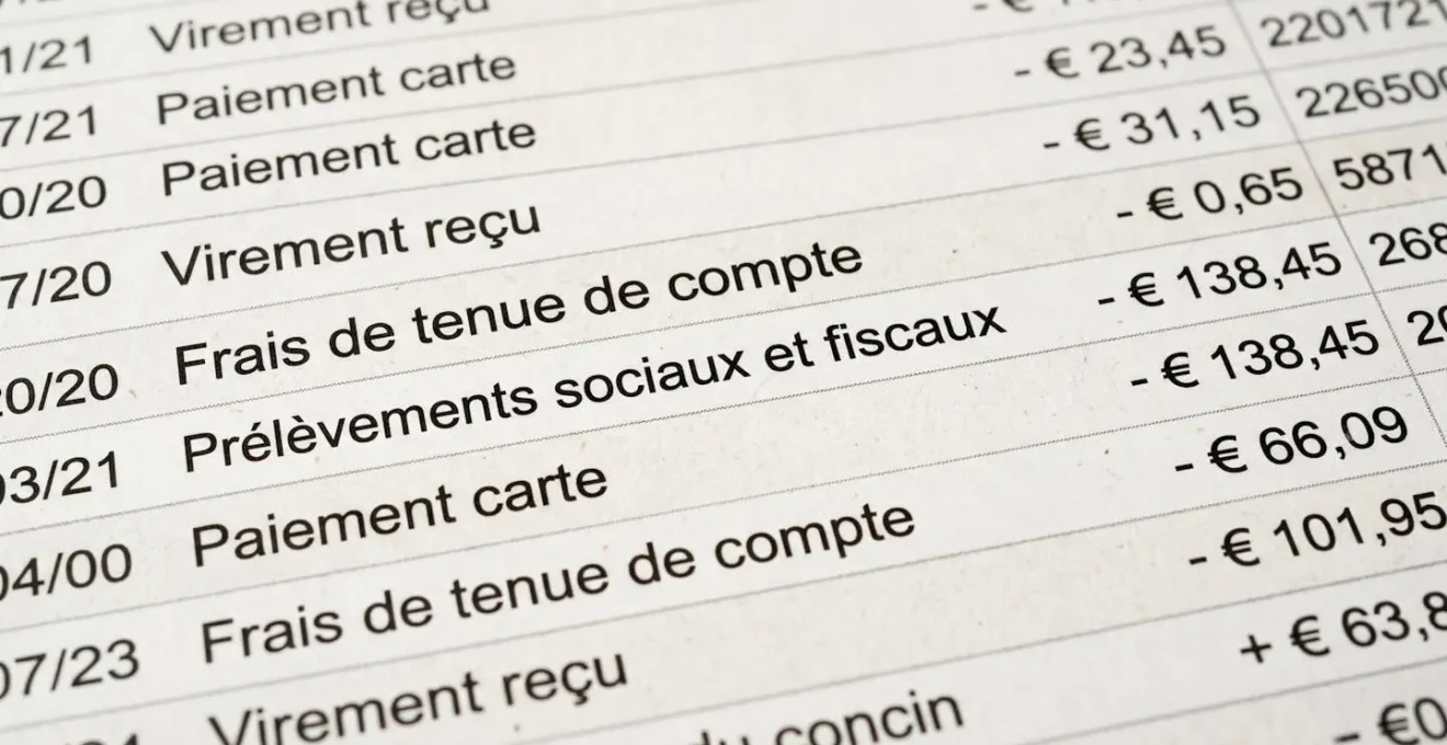 Gros plan sur un relevé bancaire affichant la ligne Prélèvements sociaux et fiscaux avec montants en euros, surface blanche moderne, lumière naturelle