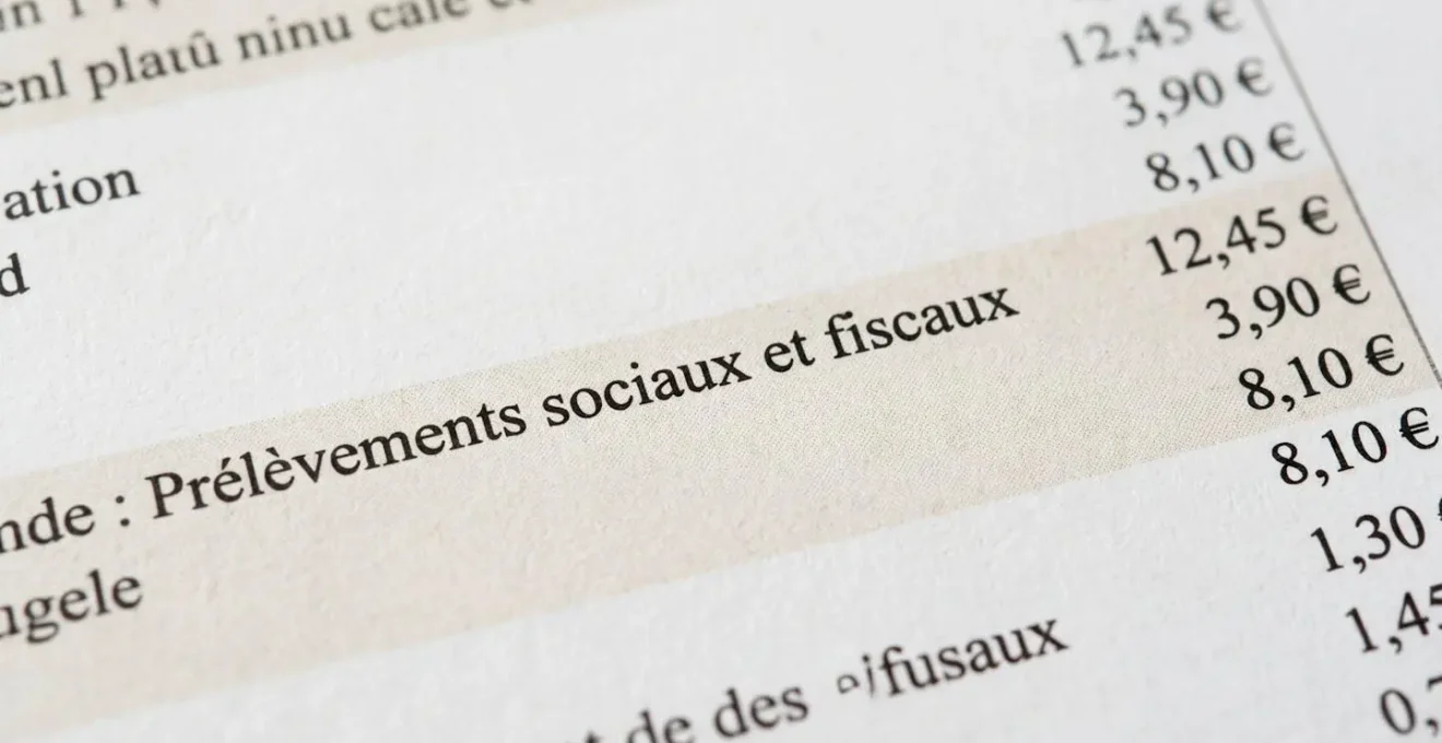 Gros plan sur un relevé bancaire affichant la ligne Prélèvements sociaux et fiscaux avec montants en euros, surface blanche moderne, lumière naturelle